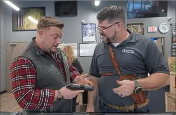  ?? Emily Matthews/Post-Gazette ?? Bill Barrett, of Jefferson Hills, left, talks to employee Chuck Masters about the pistol he is holding on Saturday at Allegheny Arms in Bethel Park. Mr. Barrett said he ended up buying a Sig Sauer 9mm handgun.