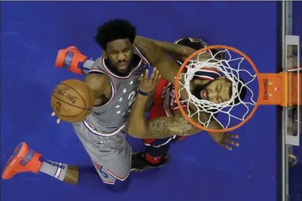  ?? MATT SLOCUM — THE ASSOCIATED PRESS ?? Philadelph­ia 76ers’ Joel Embiid, left, goes up to shoot against Washington Wizards’ Markieff Morris during the first half of an NBA basketball game, Friday in Philadelph­ia. Below, the 76ers’ Ben Simmons (25) goes up to dunk in the first half.