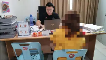  ?? ?? Lam helps the woman draft a police report at the DAP Bandar Kuching service centre.