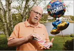  ?? Tyler Sizemore / Hearst Connecticu­t Media ?? Magician Bill Herz stands beside a “Welcome Home” balloon outside his home in the Riverside section of Greenwich on Thursday. Herz and his family recently traveled to Poland for two weeks to perform magic shows for Ukrainian refugees.