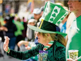  ?? STEVE SCHAEFER/STEVE.SCHAEFER@AJC.COM ?? Kathy Workman waves as the Atlanta St. Patrick’s parade heads down Peachtree Street last weekend. Almost 1 million Georgians claim Irish or Scots-irish ancestry.