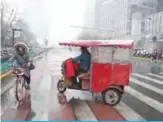  ?? —AFP ?? BEIJING: An electric pedicab rider waits for customers in Beijing’s central business district yesterday. China yesterday posted better-than-expected economic data for November, giving further breathing space to Beijing after the country agreed a partial trade deal with the US last week.