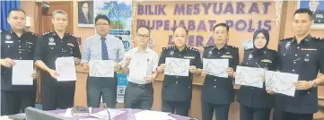  ??  ?? Ng (fourth right), Kuching Marathon 2018 director Liew Tang Chieh (fourth left) and other police personnel hold up printouts of the route for the 2018 Kuching Marathon which will take place tomorrow.
