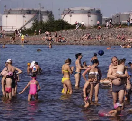  ?? © ?? Mensen zwemmen nabij een Russische olietermin­al in Sint-Petersburg.
Dmitri Lovetsky/ap