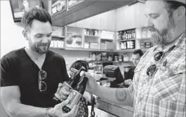  ??  ?? JEREMY FRAYE, right, general manager of the Oaks Gourmet Market, hands McHale some bottles of Pliny the Elder, a beer sold only in select dispensari­es.