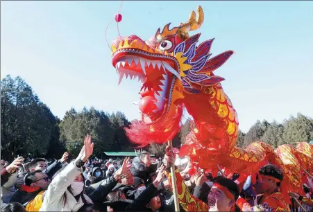  ?? CHEN XIAOGEN / FOR CHINA DAILY ?? Tourists try to touch a dragon for good luck at a Spring Festival cultural temple fair in Beijing on Feb 15.