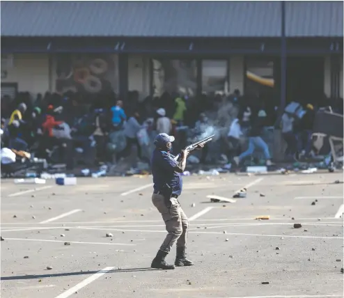  ?? GUILLEM SARTORIO / AFP VIA GETTY IMAGES ?? A member of the South African Police Service fires rubber bullets at rioters looting the Jabulani Mall in Soweto,
southwest of Johannesbu­rg, on Monday, amid unrest sparked by the jailing of ex-president Jacob Zuma.