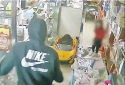  ??  ?? CALLOUS: A worker’s young daughter runs for cover as two men, one with a gun (right), burst into a Morris Heights bodega Sunday. They got away with $700 in the second robbery at the store in two weeks.