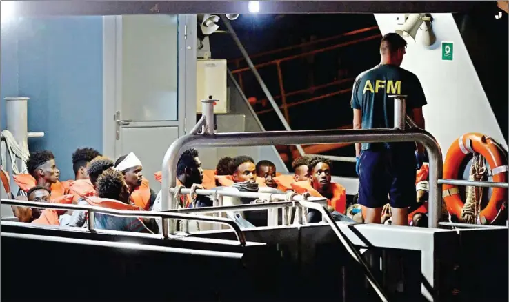  ?? MATTHEW MIRABELLI/AFP ?? Migrants, part of a group of 65 rescued by the German-flagged NGO rescue ship Alan Kurdi, sit in a patrol boat as they are brought into Haywharf, in Valletta, by the Armed Forces of Malta after being transferre­d onto the Maltese patrol boat on Sunday.