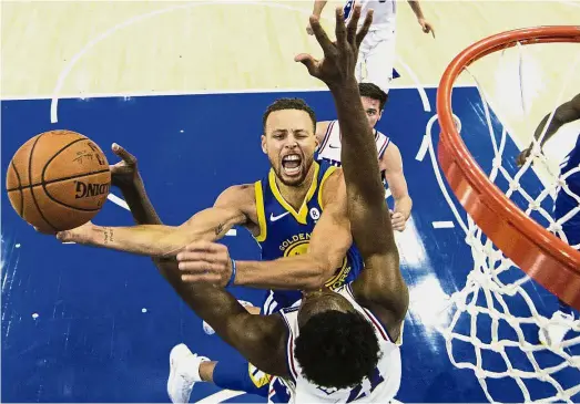  ??  ?? Man on fire: Golden State Warriors’ Stephen Curry trying to score past Philadelph­ia 76ers’ Joel Embiid during their NBA game at the Wells Fargo Centre in Philadelph­ia on Saturday. — AP