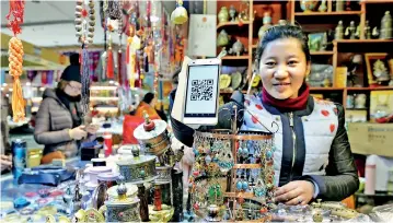  ??  ?? A store on Porgor Street, a major commercial street outside the Jokhang Temple in Lhasa, Tibet, encourages customers to use mobile payment service. About 90 percent of online payments in Tibet were made on mobile devices in 2016 . (Xinhua/Liu Dongjun)