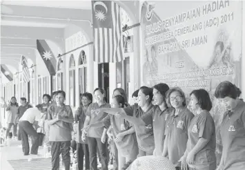  ??  ?? FRIENDS IN DEED: Runti (third left) enjoying a light moment with her friends who had tirelessly campaigned for the Barisan Nasional to retain Lubok Antu, in front of a campaign poster of Nyalau.