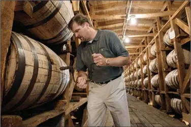  ?? (AP) ?? Jeff Arnett, then-master distiller at the Jack Daniel’s distillery in Lynchburg, Tenn., drills a hole in a barrel of whiskey in this file photo. Arnett is part of the team that’s opening Company Distilling.