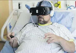  ?? LEAH HENNEL ?? Graydon Cuthbertso­n, a patient at Calgary’s Rockyview General Hospital, uses a virtual reality device while receiving wound care on his severelyin­jured legs. He says the technology eases his stress.