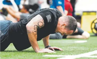  ??  ?? Scott Jenkins does push-ups Friday as part of the Maltz Challenge, which this year honors David Carter, an Aurora national guardsman killed during a rescue mission in Afghanista­n in 2011.