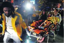  ?? Umit Bektas / Reuters; AP Photo; Emrah Gurel / AP Photo; Tolga Bozoglu / EPA ?? Left, a Turkish coast guard boat patrols in front of the Reina nightclub by the Bosphorus. Above, medics carry a wounded person at the scene after the attack. Below, a young woman cries as she leaves flowers for the victims outside the nightclub....