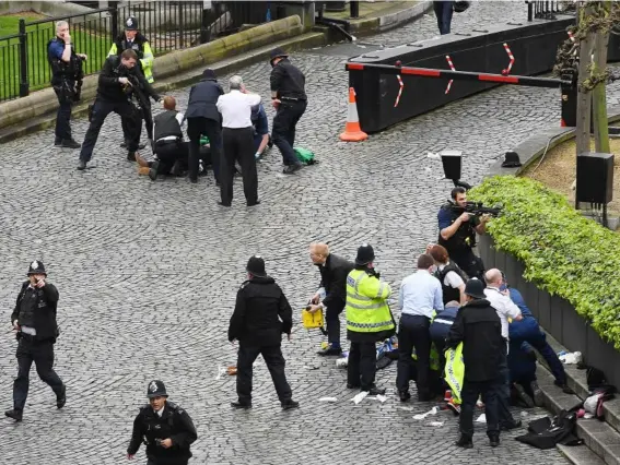  ??  ?? Chaos, as a policeman points a gun at a man on the ground, believed to be the suspect, (top) while emergency services tried to help a police officer (bottom) who died from his injuries (PA)