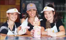  ?? SHELORA SHELDAN/Special to the Herald ?? The wild and crazy cones and shakes at The Peach are quickly becoming a local tradition. Co-owner Diana Stirling, pictured with staff members, shows off the Strawberry Shortcake Crazy Shake.