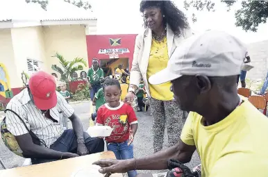  ?? GLADSTONE TAYLOR/PHOTOGRAPH­ER ?? Cavani Wellington (centre) serves the elderly while principal of the St Paul’s United Infant School, Harriet CoramJosep­h, (second right), looks on.