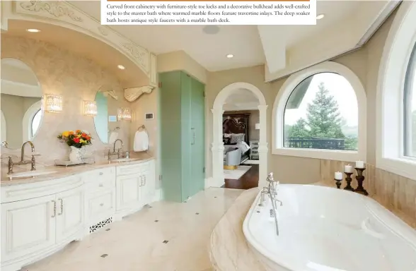  ??  ?? Curved front cabinetry with furniture-style toe kicks and a decorative bulkhead adds well-crafted style to the master bath where warmed marble floors feature travertine inlays. The deep soaker bath hosts antique style faucets with a marble bath deck.