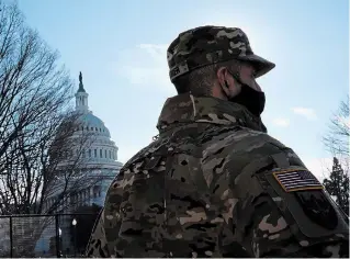 ?? MATT SLOCUM THE ASSOCIATED PRESS ?? With the U.S. Capitol in the background, a member of the District of Columbia National Guard stands near newly-placed fencing around the grounds the day after violent protests there.