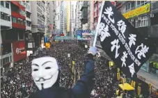  ?? — REUTERS ?? A protester wearing a Guy Fawkes mask waves a flag during massive street marches in Hong Kong on Sunday.