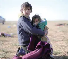  ?? — Reuters ?? A boy holds a baby near the village of Baghouz, Deir Al Zor province.