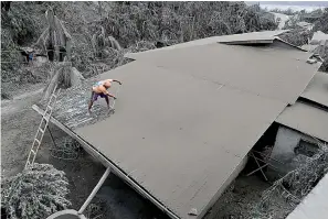  ?? AP Photo/Aaron Favila ?? ■ A resident clears volcanic ash Tuesday from his roof in Laurel, Batangas province, southern Philippine­s. Taal volcano is spewing ash half a mile high and trembling with earthquake­s constantly as thousands of people flee villages darkened and blanketed by heavy ash.