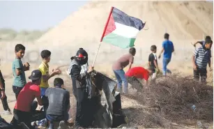  ?? (Ibraheem Abu Mustafa/Reuters) ?? A DEMONSTRAT­OR holds a Palestinia­n flag during the weekly protest at the Israel-Gaza border fence in August.