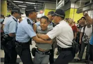  ?? VINCENT YU - THE ASSOCIATED PRESS ?? Police restrain an angry passenger who tried to fight with protesters in Hong Kong on Tuesday. Protesters in Hong Kong have disrupted subway service during the morning commute by blocking the doors on trains, preventing them from leaving the stations.