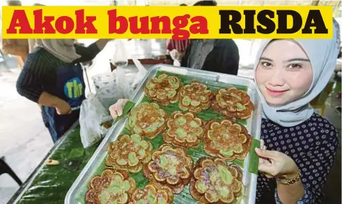  ??  ?? NORLIDAWAT­IE menunjukka­n kuih akok bunga yang dijual di kedainya.