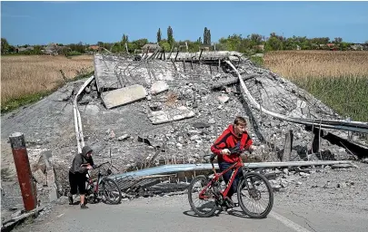  ?? AP ?? Teenagers on bicycles pass a bridge destroyed by Russian shelling near Orihiv, Ukraine. Ten weeks into the devastatin­g war, Ukraine’s military says it has recaptured some areas in the south and repelled other attacks in the east.