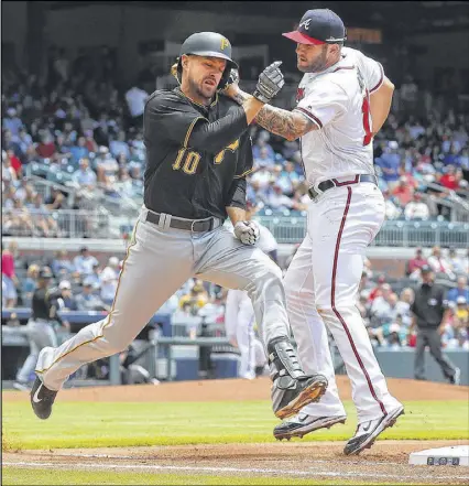  ?? CURTIS COMPTON / CCOMPTON@AJC.COM ?? The Pirates’ Jordy Mercer is safe at first as the Braves’ Matt Adams loses his handle on the ball in Thursday’s second inning in Atlanta. The Braves blew a chance to close out a series victory as the Pirates pounded starter Bartolo Colon.