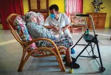  ?? Lionel Bonaventur­e / Getty Images ?? Rosalie Jalbert, 102, who tested positive for COVID-19, chats with a worker at Le Coustil retirement home in Salles, France.