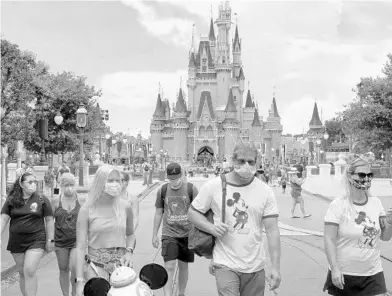  ?? JOE BURBANK/ORLANDO SENTINEL ?? Guests wear masks as required to attend the official reopening day of the Magic Kingdom at Walt Disney World on July 11.