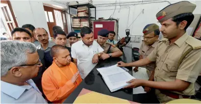  ?? PTI ?? Yogi Adityanath speaking with a police personnel during a surprise visit at the Hazratganj police station in Lucknow on Thursday. —