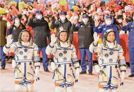  ?? Xinhua News Agency ?? Chinese astronauts Fei Junlong, Deng Qingming and Zhang Lu wave before their spaceship blasted off from the Gobi Desert.