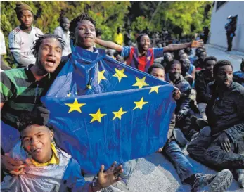  ?? FOTO: DPA ?? Flüchtling­e in der spanischen Exklave Ceuta mit einer EU-Flagge.
