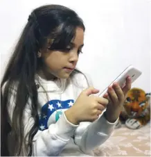  ??  ?? ALEPPO: Syrian Bana Al-Abed, who with the help of her mother had been posting heart-rending tweets in English on life in the besieged eastern districts of Syria’s Aleppo, uses a smart-phone to check her Twitter account in her home in east Aleppo. — AFP