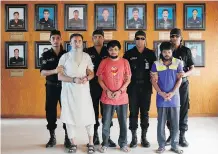  ?? A. M. AHAD/ THE ASSOCIATED PRESS ?? Bangladesh Rapid Action Battalion personnel, in black, present suspected members of a banned Islamic militant outfit in Dhaka, suspected in the killings two secular bloggers.