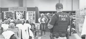  ?? AFP/GETTY IMAGES ?? A Homeland Security Investigat­ions officer guards suspected undocument­ed workers Wednesday. Officers detained 680 people at food processing plants across Mississipp­i last week, an operation that took place after a mass shooting in Texas that targeted Hispanics.