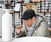  ?? ?? Yu Xiaofu pauses thoughtful­ly before applying his brush to the porcelain vase. — Photos by Dong Hong