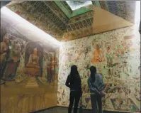  ?? GAO ZHAN / CHINA NEWS SERVICE ?? Tourists in Lanzhou, Gansu province, take in a copy of a mural from the Dunhuang Mogao Grottoes in May 2020.