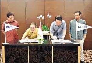  ?? YUNKI/ANTARA/THE JAKARTA POST ?? Diversifie­d conglomera­te Astra Internatio­nal president director Prijono Sugiarto (second left) and ride-hailing app giant Go-Jek president and co-founder Andre Soelistyo (second right) sign an agreement in Jakarta recently, as Go-Jek CEO and co-founder Nadiem Makarim (right) and Astra Internatio­nal director Bambang Widjanarko Santoso look on.