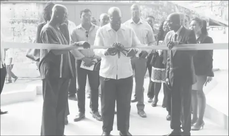  ??  ?? Minister of Finance Winston Jordan (at centre) cutting the ribbon to officially commission the warehouse along with Managing Director Andrew Astwood (right)