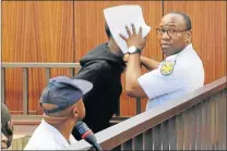  ?? Picture: MALIBONGWE DAYIMANI ?? COVER UP: A court guard, Sergeant Chuma Ngaka, shields the face of a suspect charged in the murder of a 59-year-old woman from being photograph­ed by the Daily Dispatch