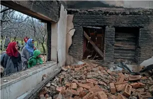  ?? AFP ?? Kashmiri villagers stand next to the remains of a house destroyed during a deadly gun battle between militants and government forces in the Pinglish area of Tral, Pulwama district, on Monday. —