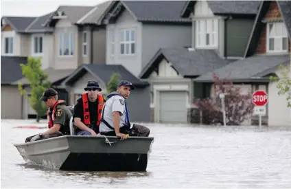  ?? JEFF MCINTOSH/ THE CANADIAN PRESS ?? RCMP return from a boat patrol of a flooded neighbourh­ood in High River. They have come under fire for seizing unsecured weapons.