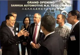  ?? CHANG JUN / CHINA DAILY ?? Zhang Daocai (left), chairman of the Zhejiang-based Sanhua group that specialize­s in thermal management, greets guests at the grand opening of Sanhua Automotive North America Tech Center on Thursday in Detroit, Michigan.