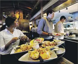  ?? Elaine Thompson Associated Press ?? A NEW STUDY finds a big drop in jobs and income among Seattle’s lowest-paid workers after the city’s minimum wage rose. Above, workers at a Seattle eatery.